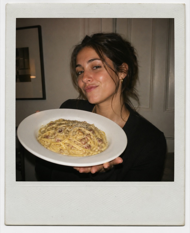 Polaroid of a girl holding a plate of spaghetti carbonara